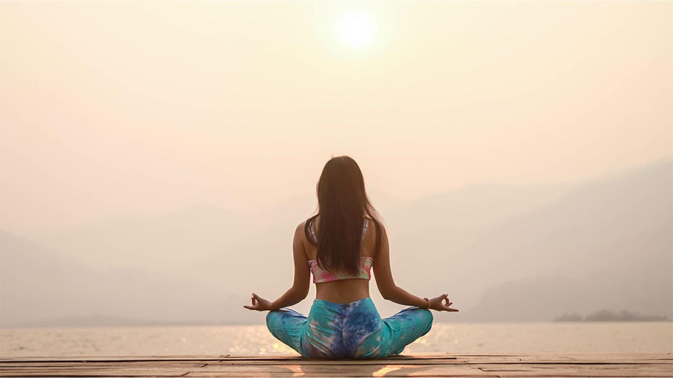 A woman practicing yoga on a beach
